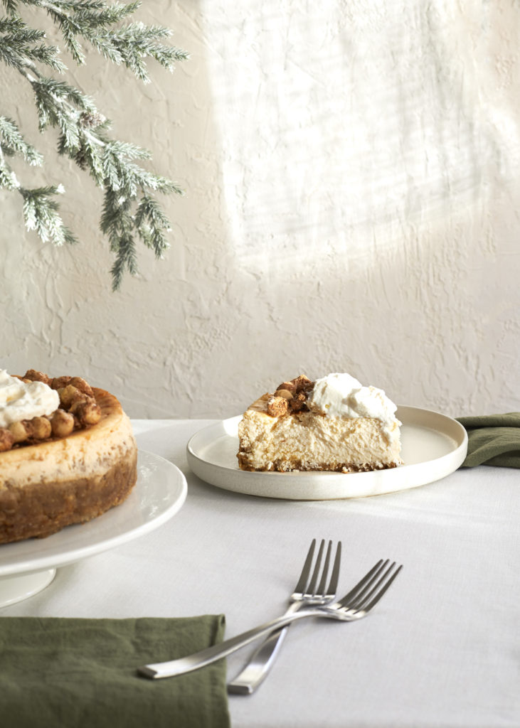 gluten free eggnog cheesecake with a graham cracker crust topped with eggnog whipped cream and candied hazelnuts