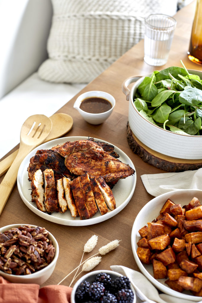 spicy chicken grain bowl filled with spicy chicken, coconut quinoa, cinnamon sweet potatoes, cucumbers, pecans, blackberries, cherry tomatoes and a  balsamic glaze