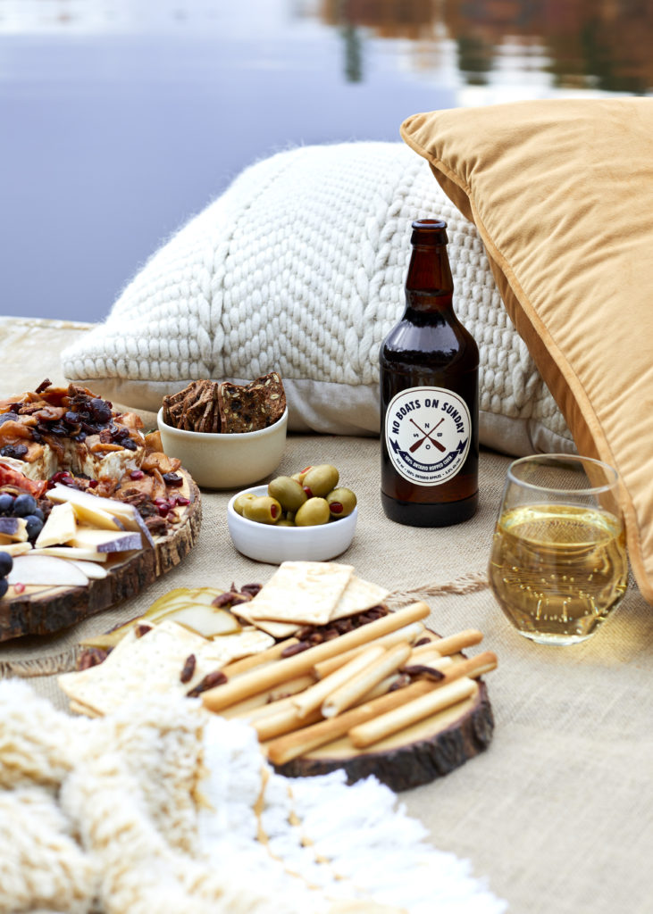 fall charcuterie board with meat, cheese, brie, merlot, spiked cider, no boats on sunday cider, olives, figs, pecans, grapes, pears and pomegranates. 