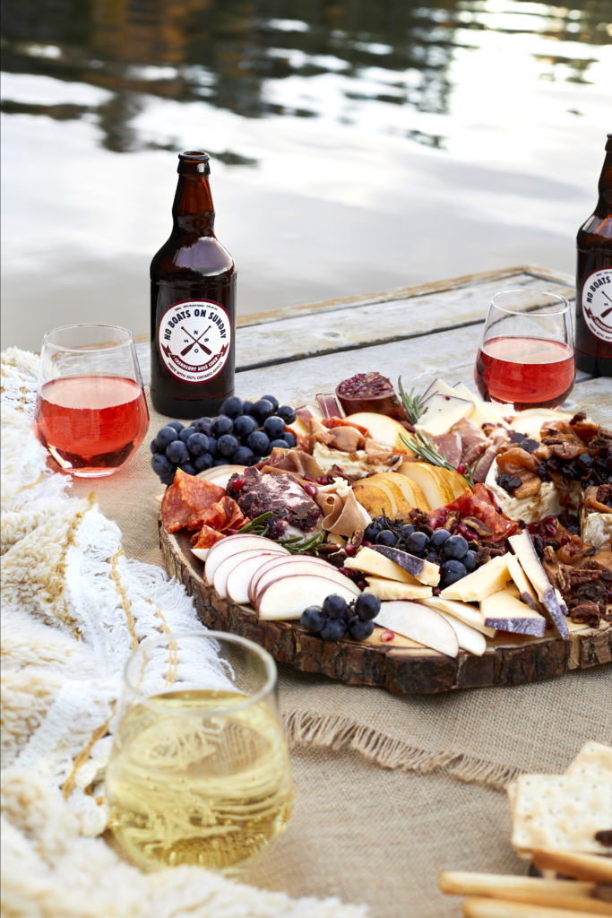 fall charcuterie board with meat, cheese, brie, merlot, spiked cider, no boats on sunday cider, olives, figs, pecans, grapes, pears and pomegranates. 