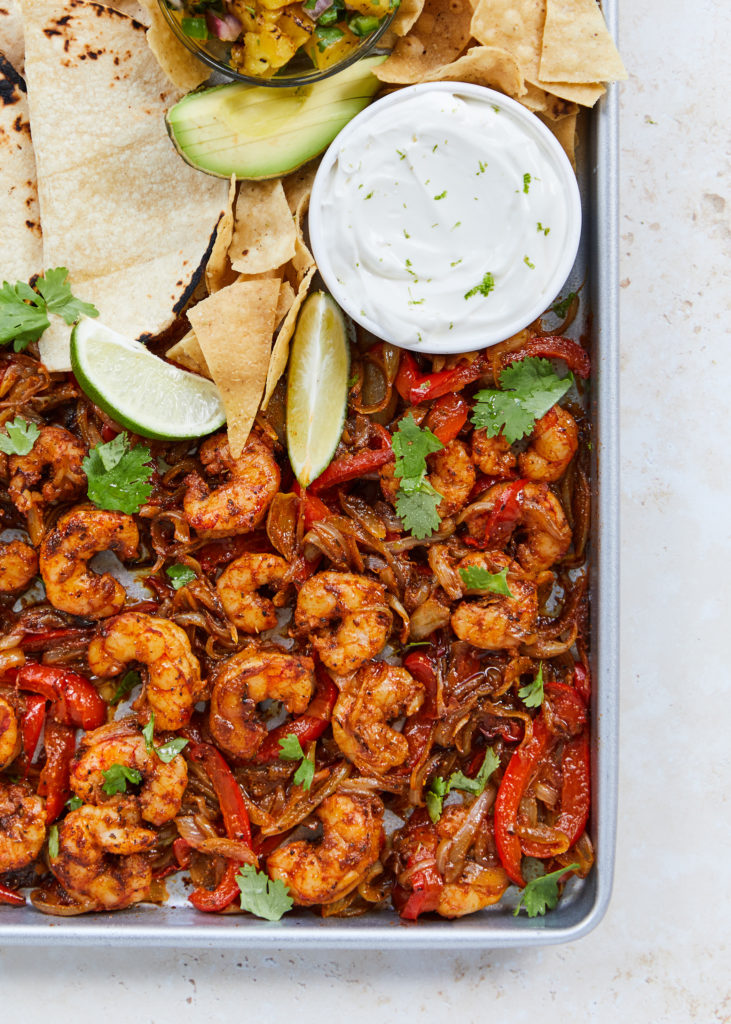 cajun shrimp fajitas with pineapple salsa, avocado, corn tortillas, lime and chips